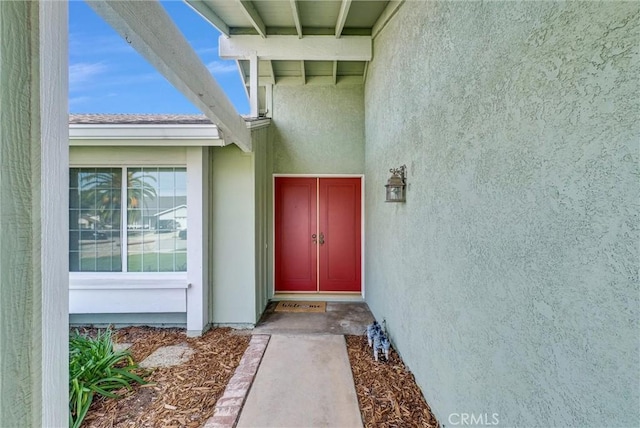 doorway to property featuring roof with shingles and stucco siding