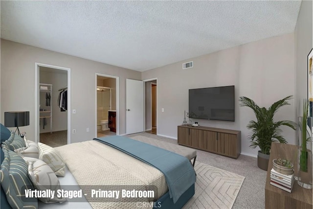 bedroom with visible vents, a textured ceiling, connected bathroom, baseboards, and light colored carpet