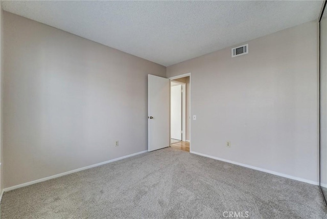 unfurnished room with visible vents, carpet floors, a textured ceiling, and baseboards