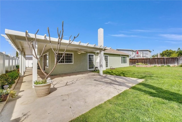 back of house with a ceiling fan, a yard, a fenced backyard, stucco siding, and a patio area