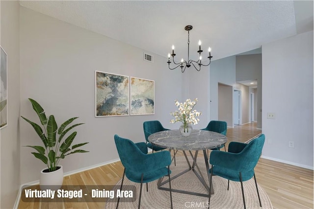 dining room with a textured ceiling, wood finished floors, visible vents, and baseboards