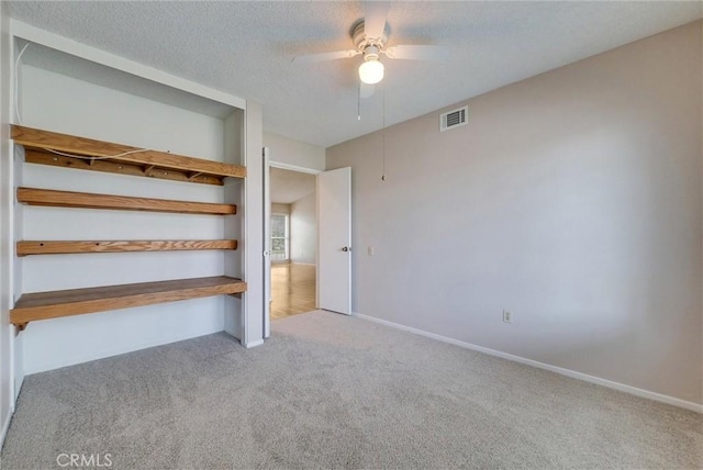 unfurnished bedroom with visible vents, a textured ceiling, baseboards, and carpet floors