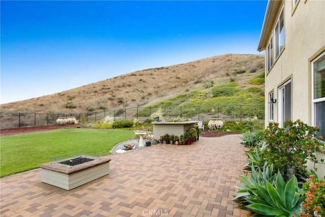 view of patio featuring a mountain view, a fire pit, and a fenced backyard