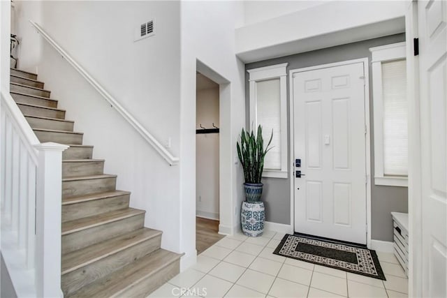 entrance foyer with tile patterned floors, visible vents, baseboards, and stairs