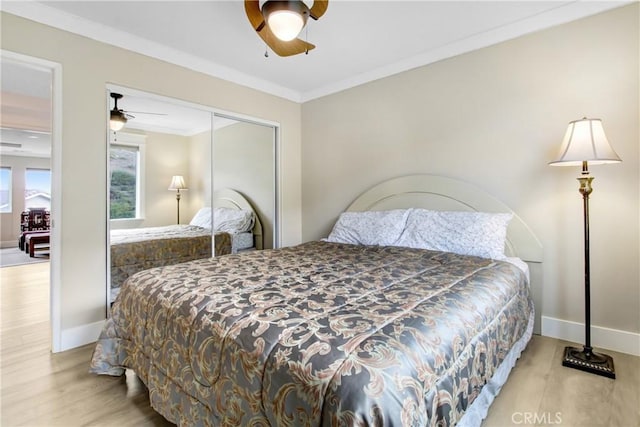 bedroom with baseboards, wood finished floors, a closet, and ornamental molding