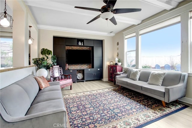 living area with beamed ceiling, a ceiling fan, baseboards, and wood finished floors