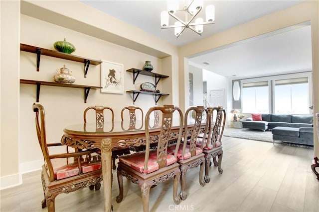 dining space with light wood-type flooring, baseboards, and a notable chandelier