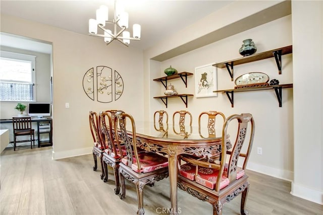 dining area featuring light wood-type flooring, baseboards, and a notable chandelier