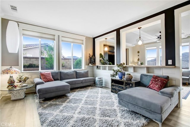 living room with crown molding, wood finished floors, and visible vents