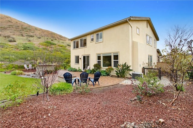 back of house with stucco siding, a patio, central AC, fence, and a mountain view