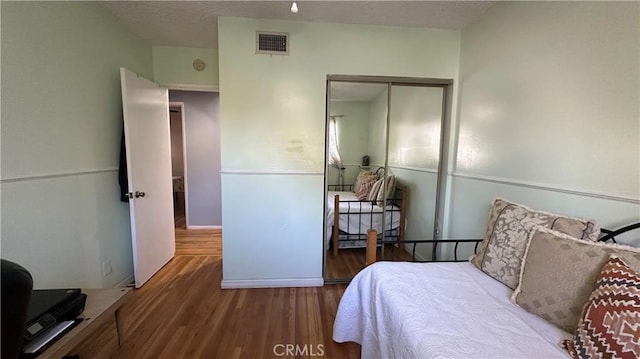 bedroom featuring visible vents, a textured ceiling, a closet, and wood finished floors