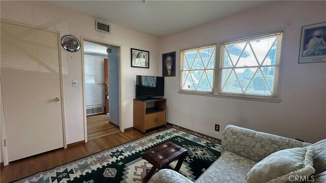 living area with wood finished floors, visible vents, and baseboards