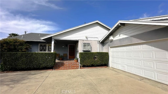 view of front of house featuring stucco siding, covered porch, and driveway