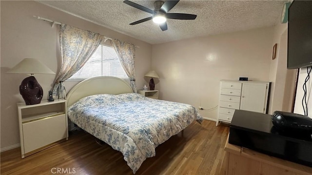 bedroom with ceiling fan, baseboards, a textured ceiling, and wood finished floors