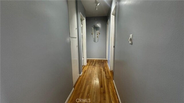 hallway with baseboards and wood finished floors