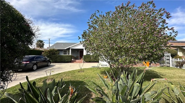 obstructed view of property featuring a front yard, concrete driveway, and fence