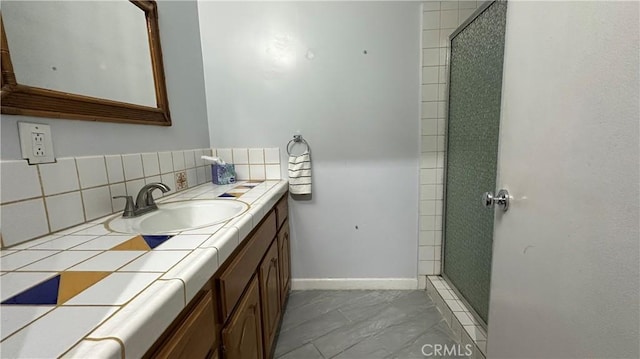 full bath featuring vanity, tasteful backsplash, baseboards, and a stall shower