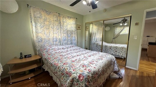 bedroom with a ceiling fan, a textured ceiling, wood finished floors, a closet, and baseboards