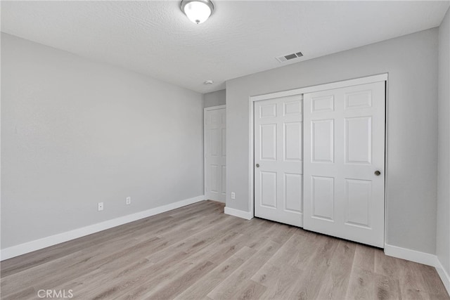 unfurnished bedroom with visible vents, baseboards, a closet, and light wood finished floors