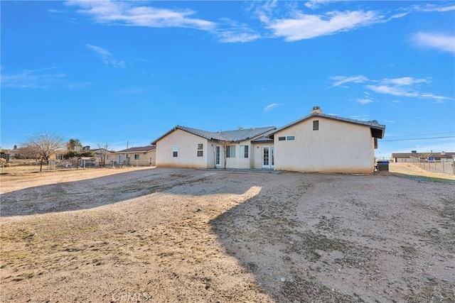 back of property with stucco siding and fence