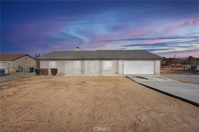 ranch-style house with concrete driveway, an attached garage, fence, and stucco siding