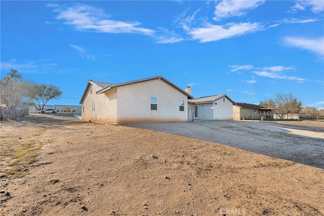 view of side of home featuring a patio area, fence, and stucco siding