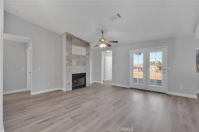 unfurnished living room featuring light wood finished floors, visible vents, a fireplace, and baseboards