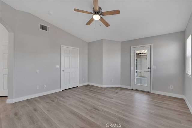 spare room with arched walkways, visible vents, light wood-style flooring, and lofted ceiling