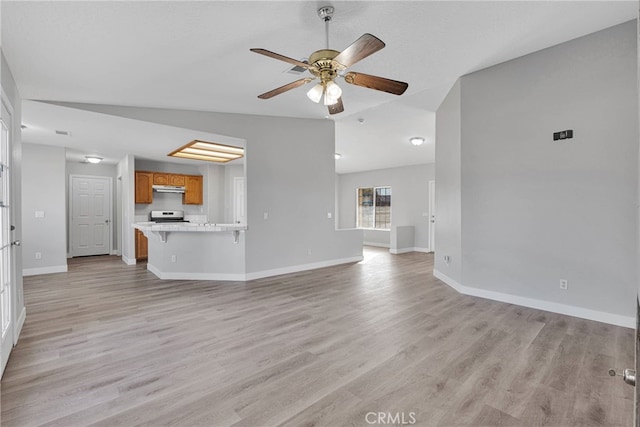 unfurnished living room featuring vaulted ceiling, baseboards, light wood-style floors, and a ceiling fan