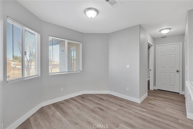 unfurnished room featuring baseboards, visible vents, and light wood-type flooring