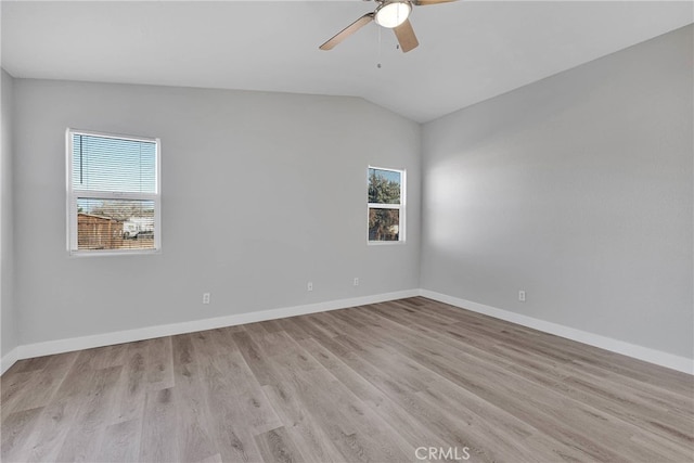 spare room with vaulted ceiling, a ceiling fan, baseboards, and light wood finished floors