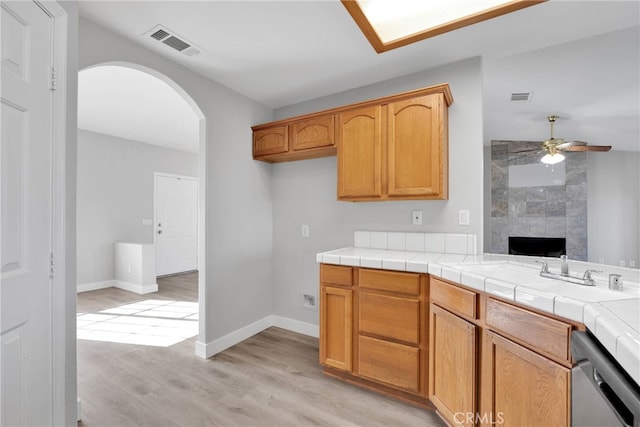 kitchen featuring visible vents, arched walkways, stainless steel dishwasher, and light wood-style flooring