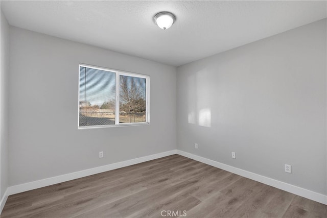 unfurnished room featuring baseboards and wood finished floors