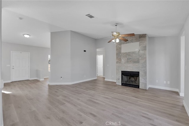 unfurnished living room with visible vents, a fireplace, baseboards, and light wood-style floors