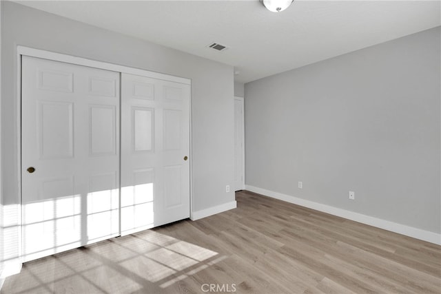 unfurnished bedroom featuring visible vents, wood finished floors, a closet, and baseboards