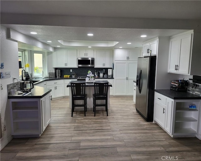 kitchen featuring stainless steel microwave, white cabinets, fridge with ice dispenser, and open shelves