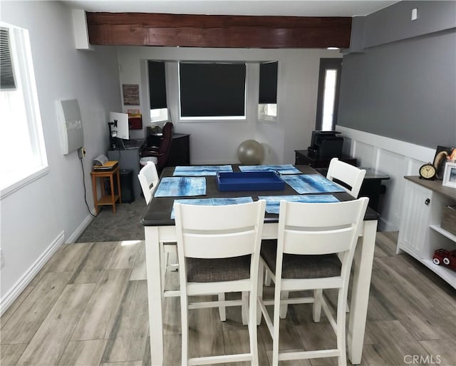 dining area featuring beam ceiling, light wood-style floors, and baseboards