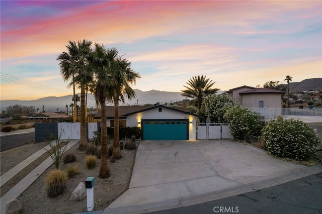 view of front of property with fence, driveway, a mountain view, and a garage
