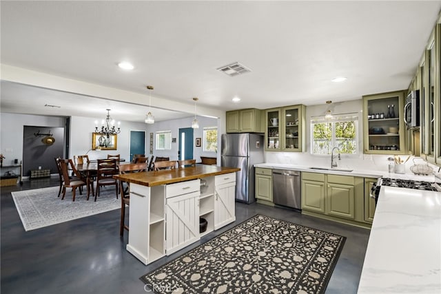 kitchen featuring a sink, butcher block countertops, appliances with stainless steel finishes, and green cabinetry