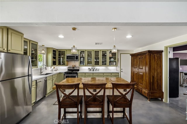 kitchen with appliances with stainless steel finishes, finished concrete floors, a sink, and green cabinetry