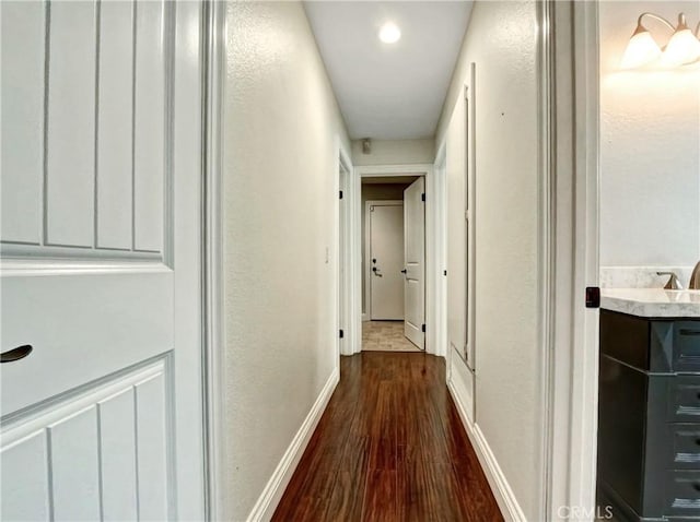 hall featuring dark wood-style floors and baseboards