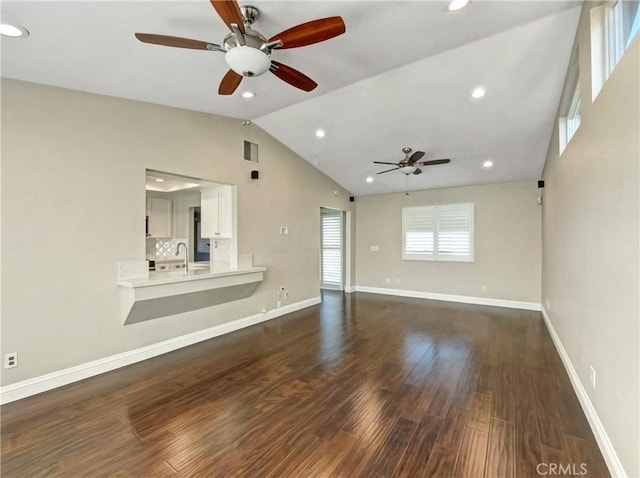 unfurnished living room featuring baseboards, recessed lighting, a sink, dark wood-type flooring, and vaulted ceiling