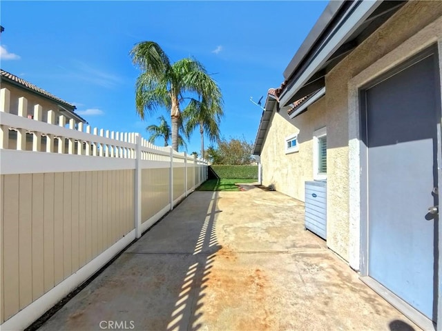 view of side of home featuring a patio area, stucco siding, and fence