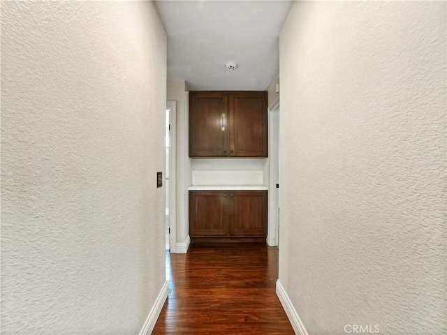 hall with baseboards, dark wood-type flooring, and a textured wall