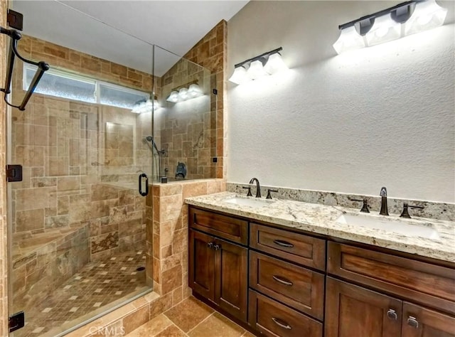 bathroom with double vanity, a stall shower, and a sink