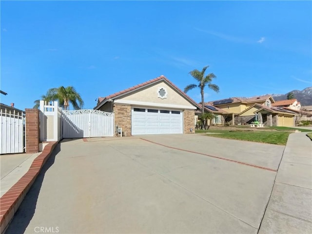 view of front of home with a garage, concrete driveway, stucco siding, and a gate