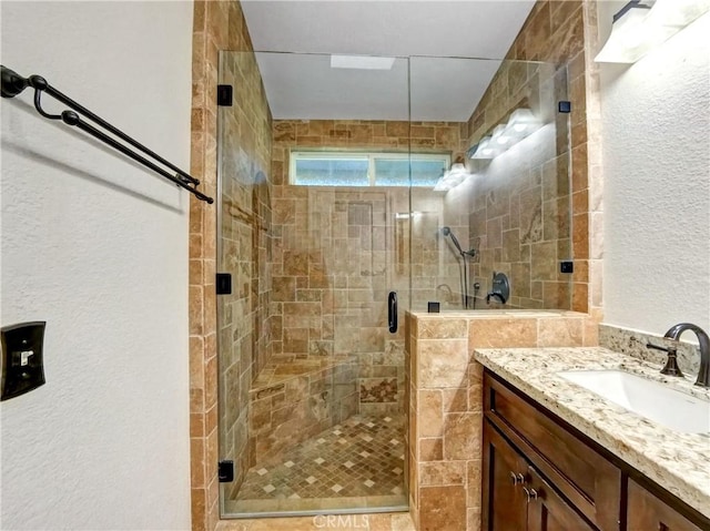 bathroom featuring vanity, a shower stall, and a textured wall