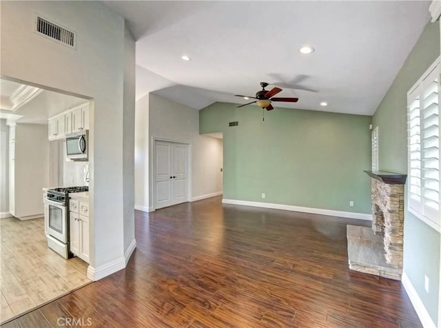 unfurnished living room with visible vents, baseboards, a fireplace, wood finished floors, and a ceiling fan