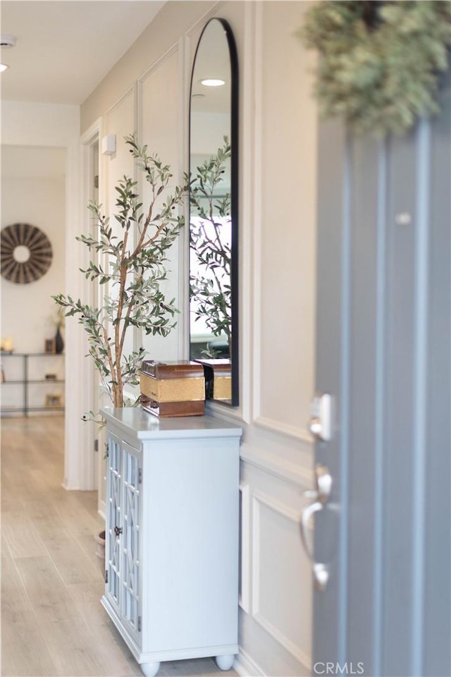 foyer with light wood-style floors and a decorative wall