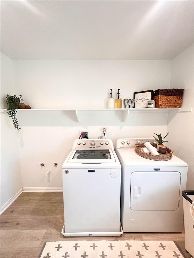 clothes washing area with washing machine and clothes dryer, laundry area, and light wood finished floors